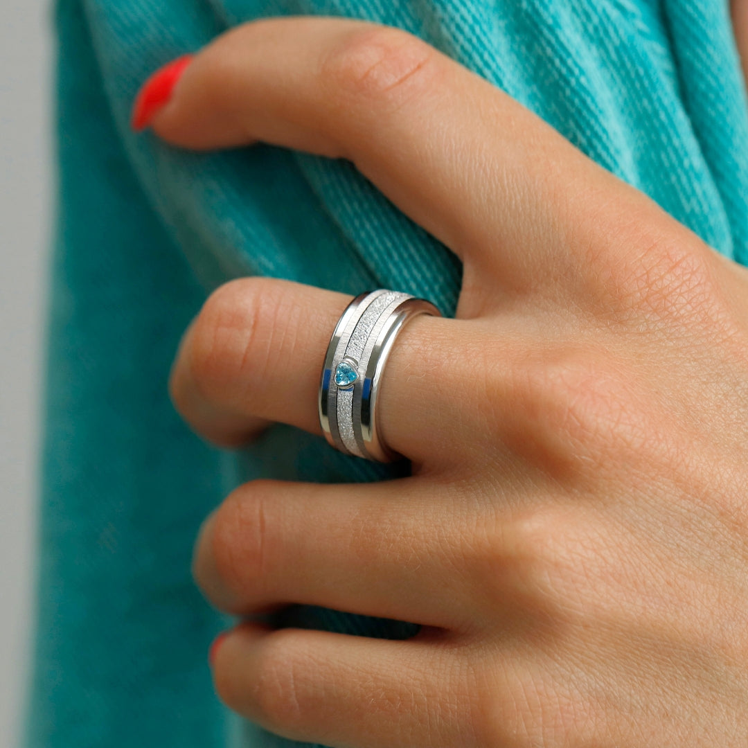 bague en argent avec brillant bleu en forme de coeur et anneaux interchangeables en acier inoxydable de la marque mood sur main de femme